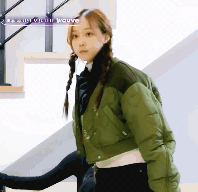 a woman wearing a green jacket with the word wavve on the bottom