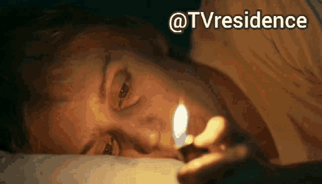 a woman is laying on a bed lighting a lighter with the words @tvresidence behind her