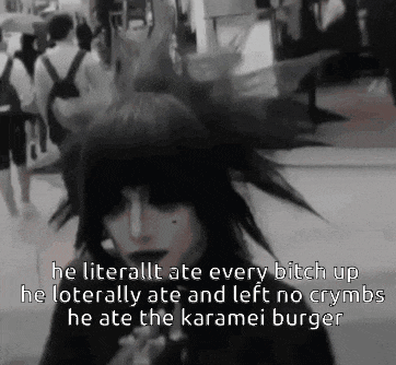 a black and white photo of a person with a mohawk eating a hamburger