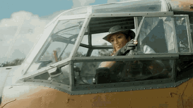 a woman wearing a cowboy hat is sitting in the cockpit of a plane