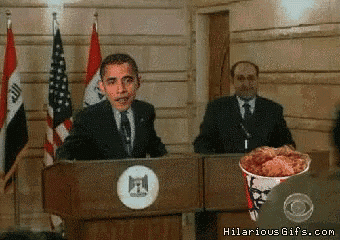 a man giving a speech with a bucket of fried chicken behind him