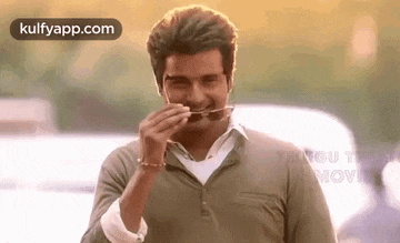 a man is eating something with a straw in his mouth while wearing sunglasses .