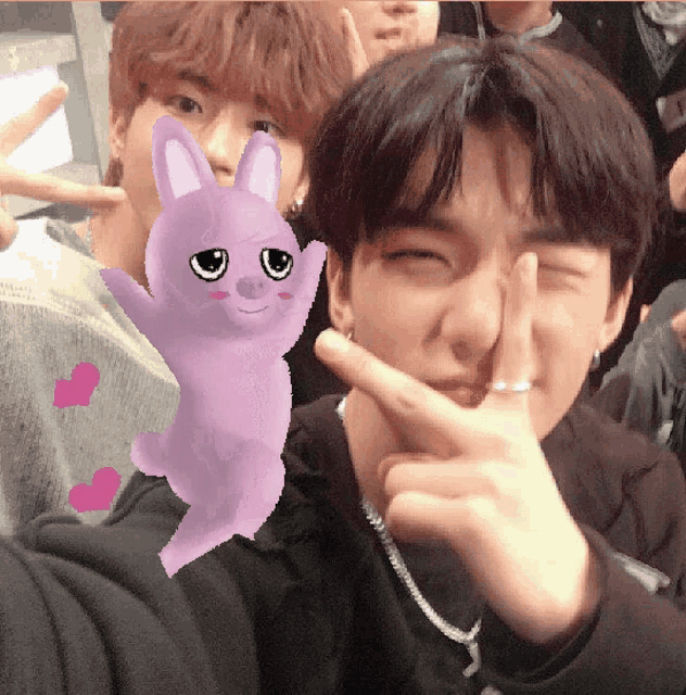 a purple stuffed animal with bunny ears is next to a man