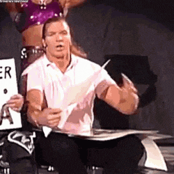 a man is sitting on a chair holding a piece of paper and a woman is standing behind him .