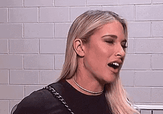 a close up of a woman 's face with her mouth open in front of a white brick wall .
