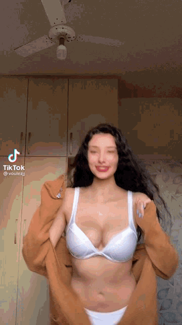 a woman in a bra and panties is taking off her sweater