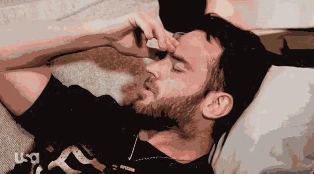 a man with a beard is laying on a bed with a usa logo in the background