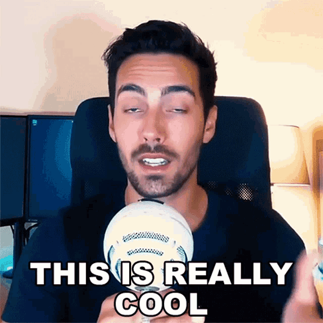 a man with a beard is talking into a microphone and the words " this is really cool " are above him