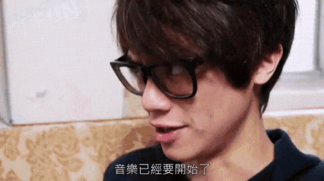 a man wearing glasses and a black shirt is speaking in chinese