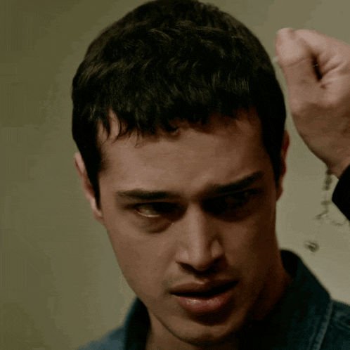a close up of a man 's face with a hand on his hair