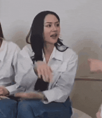 a woman in a white shirt is sitting on a bed talking to another woman .