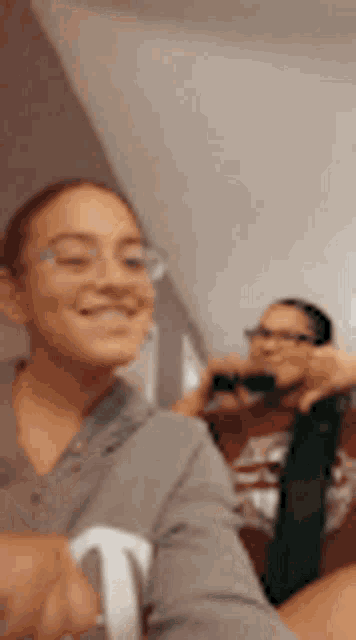 a woman is taking a selfie with her phone while another woman takes a picture of her .