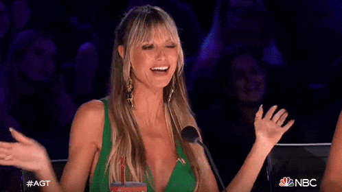 a woman in a green dress is sitting in front of a microphone with her arms in the air .