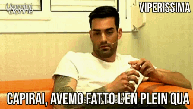 a man in a white shirt is sitting on an orange couch with the words viperissima written above him