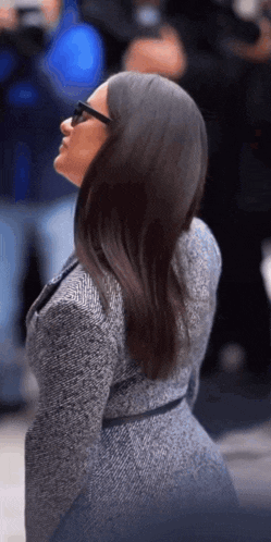 a woman in a gray coat and sunglasses is looking up .