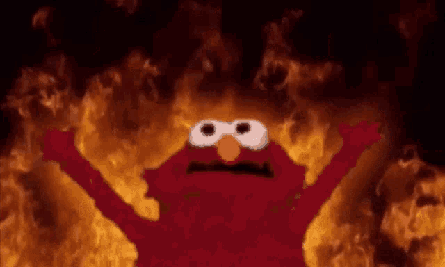 elmo from sesame street is standing in front of a fire with his arms outstretched .