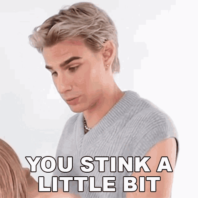 a man in a grey vest says " you stink a little bit " in white letters