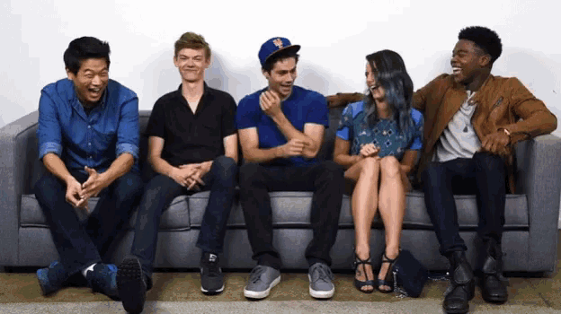 a group of people are sitting on a couch with one wearing a hat that says ny