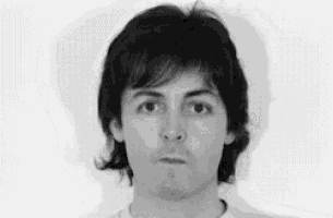 a black and white photo of a man with long hair making a face .