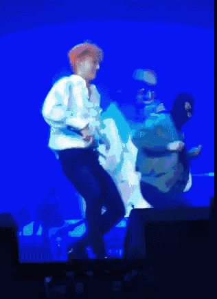 a man in a white shirt is dancing on a stage