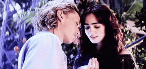 a man is kissing a woman on the forehead while holding her hand .