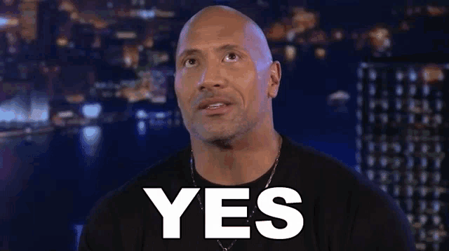 a bald man says yes in front of a city at night