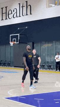 a man is playing basketball on a court in front of a sign that says `` health '' .