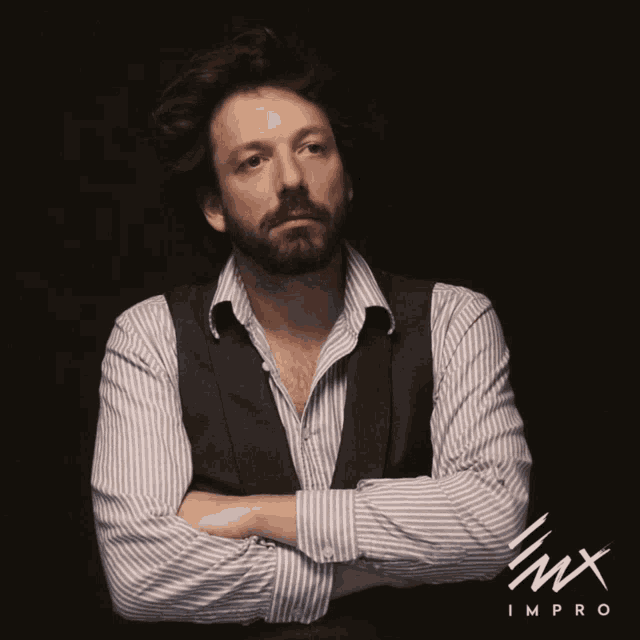 a man stands with his arms crossed in front of a black background that says imx impro