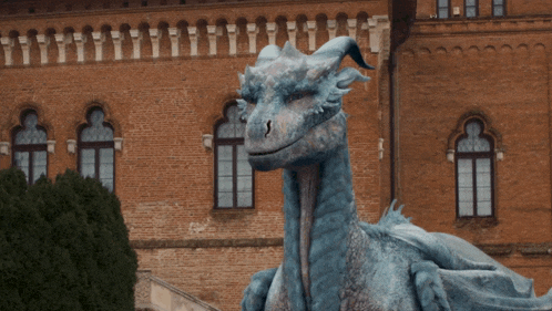 a statue of a dragon is in front of a large brick building