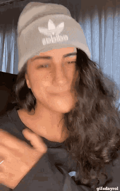a woman wearing a beanie with the adidas logo on it