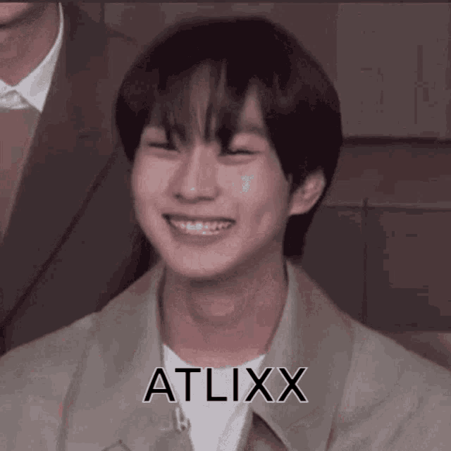a close up of a young man smiling with the word atlixx on his chest .