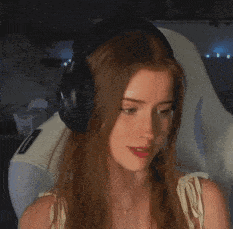 a woman wearing headphones is sitting in a chair in a dark room .