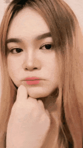 a close up of a woman 's face with her hand on her chin