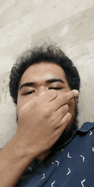 a man with a beard is covering his face with his hands