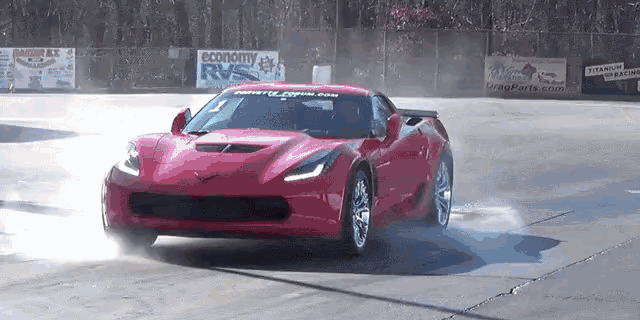 a red sports car is doing a burnout on a race track