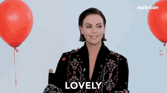 a woman sitting in front of red balloons with the word lovely on the bottom right