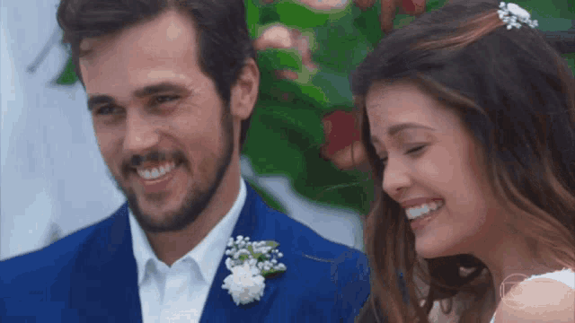a man in a blue suit and a woman in a white dress smile for the camera