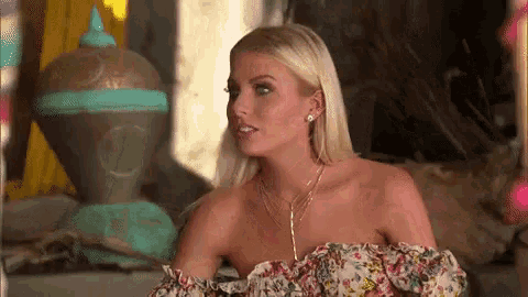a woman wearing a floral off the shoulder top is sitting in front of a statue .
