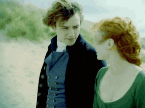 a man in a blue vest and a woman in a green dress are standing next to each other
