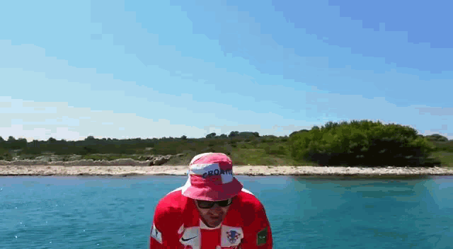 a man wearing a croatia hat and sunglasses is standing in the water
