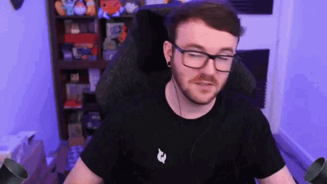 a man wearing glasses and a black shirt is sitting in front of a computer