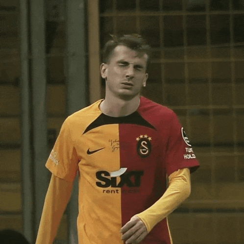 a man wearing a yellow and red shirt with sixt rent written on it