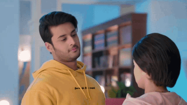 a man wearing a yellow hoodie that says " i love you " looks at a woman