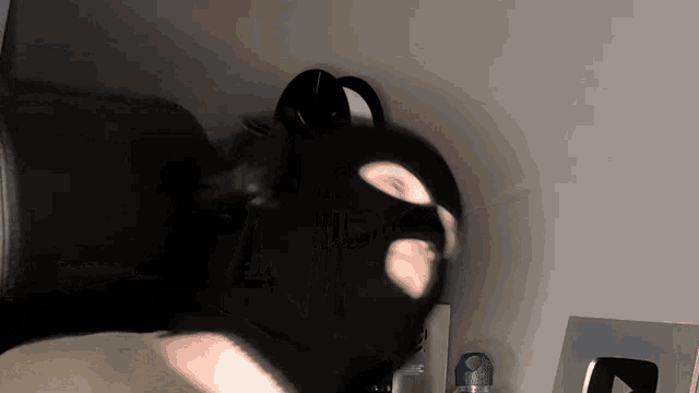 a man wearing a black mask is standing in a room