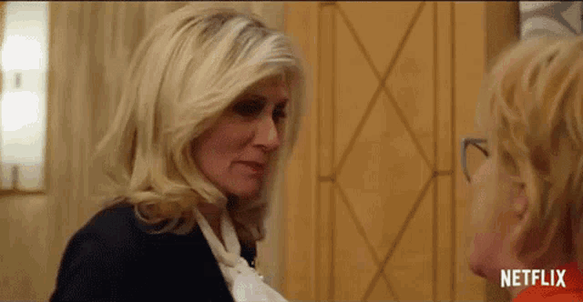 a woman in a black jacket is talking to another woman in a room .