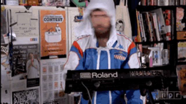 a man is playing a roland keyboard in front of a wall with a contest poster on it