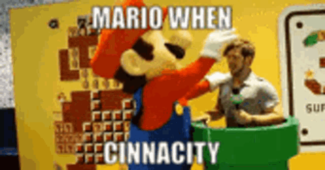 a man is standing next to a mario mascot costume .