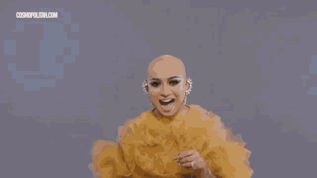 a woman wearing a crown and a yellow dress with cosmopolitan.com written on the bottom