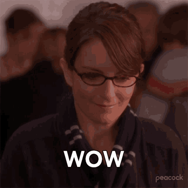 a woman wearing glasses and a scarf is smiling and says wow .