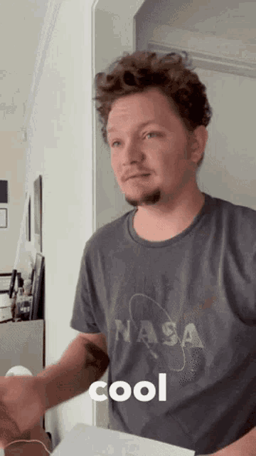 a man wearing a nasa t-shirt is standing in a hallway